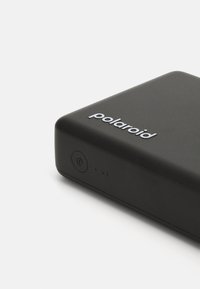 Μαύρη ορθογώνια φορητή συσκευή με λείο ματ φινίρισμα, που διαθέτει κουμπί τροφοδοσίας και ενδείξεις LED, καθώς και λογότυπο "polaroid" σε λευκό χρώμα.