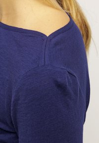 Mörkblå långärmad tröja med rund halsringning, med subtila sömdetaljer på axeln och en slät, mjuk textur.