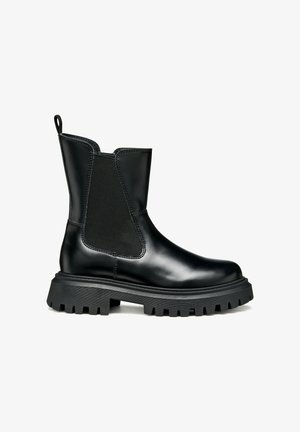 Botín de cuero negro hasta el tobillo con paneles elásticos laterales, suela de goma negra gruesa y tira en el talón para facilitar el calzado.