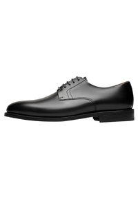 Chaussure habillée en cuir noir avec un bout arrondi, un minimum de coutures, six œillets pour les lacets et une semelle en caoutchouc plate et légèrement texturée.