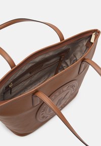Borsa a spalla in leather marrone con un esterno texturizzato, caratterizzata da un grande logo in rilievo, doppi manici e un ampio interno foderato in beige con tasche.