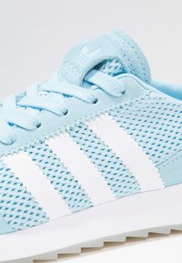 Light blue athletic shoe with mesh fabric, suede accents, white three-stripe design, and a textured rubber sole.