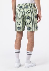 Grüne Shorts mit einem auffälligen Muster aus marineblauen Blumen und Streifen. Elastischer Bund, Gesäßtasche und Stoff mit einer strukturierten Oberfläche.