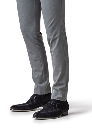 Zwarte suède veterschoenen met gladleren accenten, gecombineerd met grijze slim-fit pantalon met een subtiele textuur en een kreukdetail.