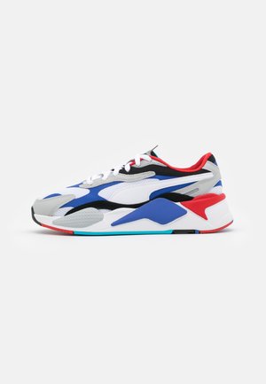 Sneaker avec une tige en mesh et synthétique grise, avec des accents noirs, bleus et rouges. Semelle épaisse avec une finition texturée et des lignes de design distinctives.