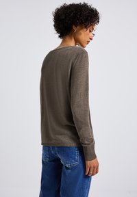 Brauner, langärmeliger Pullover mit Rundhalsausschnitt und gerippten Bündchen. Der Stoff hat eine weiche Textur mit einem leichten Glanz. Wird mit blauen, locker sitzenden Jeans getragen.