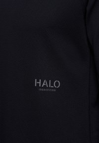 Czarna tkanina o teksturze z wzorem plastra miodu, z wytłoczonym logo "HALO" oraz numerami 1968, 1972, 1981 w jaśniejszym odcieniu.