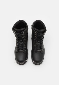 Bottes de randonnée en cuir noir avec quincaillerie métallique, bout rond, design à lacets, collier rembourré et coques renforcées pour plus de durabilité.