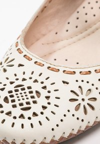 Kerman nahkakengät, joissa on leikattuja kukkakuovastoja, nahkavuori ja ommeltu reuna, pyöristetty kärki ja teksturoitu pinta.