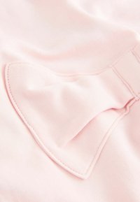 Roosa kangas, millel on silmapaistev, tekstureeritud lipsu detail. Materjal on sile kerge läikega, millele on lisatud kontrastset õmblust.