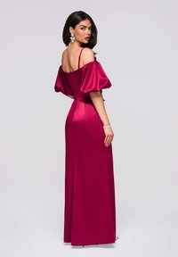 Longue robe magenta en satin, avec des manches bouffantes dénudant les épaules et un corsage ajusté, une jupe longue jusqu'au sol avec un éclat subtil.