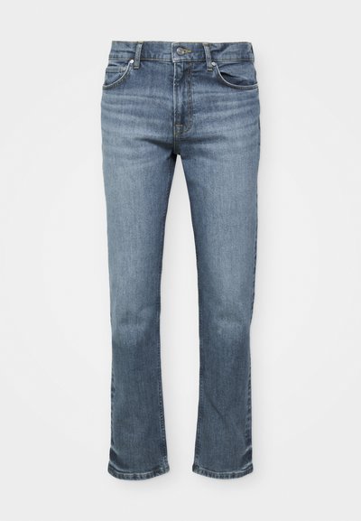 Sinine denimist valmistatud teksapüksid omavad sirget lõiget, viie tasku stiili ning nööp sulgemist, kus õmblustes on kontrastsed õmblused.