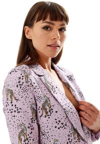 Lilac blazer with leopard print pattern, featuring a notched lapel and soft texture. Design includes various leopard placement and small black spots.