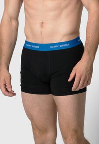 Zwarte katoenen boxershorts met een blauwe elastische tailleband met de tekst "HAPPY SHORTS". Het ontwerp is aansluitend en heeft een gladde textuur.