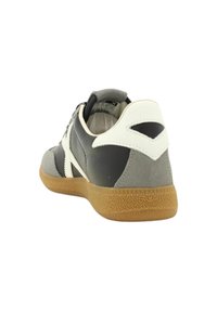 Sneaker w kolorze szarym i czarnym z białym akcentem, z teksturowaną gumową podeszwą i gładkim skórzanym wykończeniem. Okrąły czubek i sznurowany design.