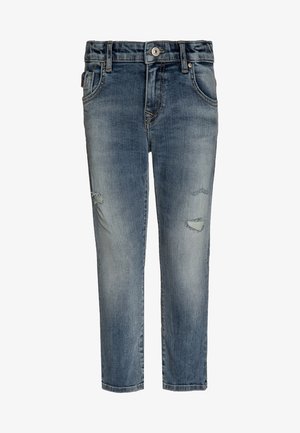 Pantalones vaqueros de mezclilla azul deslavada con ligero desgaste en los muslos, cierre de botones, bolsillos frontales y trabillas para cinturón.