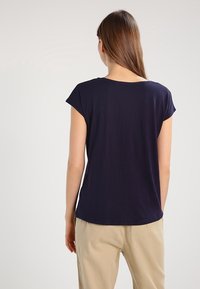 Top azul marino de manga corta con escote redondeado y ajuste holgado, fabricado en una tela suave y ligera. Diseño simple y minimalista.