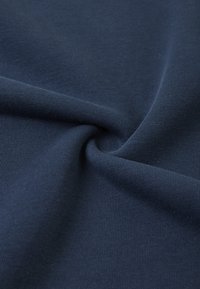 Granatowa, prążkowana tkanina, o miękkiej teksturze z delikatnymi pionowymi liniami, starannie ułożona, aby eksponować swoją elastyczność i gładką powierzchnię.