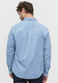  Lichtblauw overhemd met knopen, met achterpand, lange mouwen en afgeronde zoom. De stof is glad met een subtiele structuur.