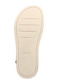 Suela de zapato de goma blanca con una superficie texturizada, ranuras horizontales para tracción y el logotipo "Clarks" en relieve.