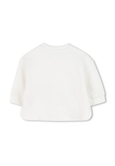 Pull blanc avec une texture douce, col rond et manches courtes. Présente des poignets côtelés et un ourlet légèrement court et arrondi.