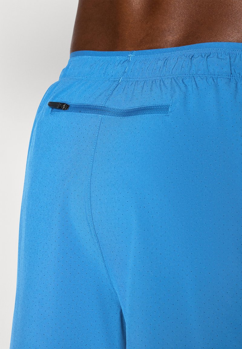 Blaue Sportshorts aus weichem, atmungsaktivem Material mit kleinen Perforationen. Enthält eine versteckte Reißverschlusstasche auf der Rückseite.