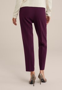 Purple tapered pants made of stretchy fabric, featuring a smooth texture and a mid-rise design, paired with beige high-heeled shoes.