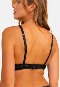 Soutien-gorge noir avec dentelle, doté de bretelles réglables et d'une fermeture à crochet. Matériau doux avec une texture lisse.