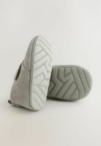 Grå texturerade skor i mjukt mockamaterial med en gummisula som har ett zigzag-mönster för bra grepp.