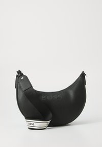 Bolso de mano de cuero negro con forma de media luna, superficie texturizada, logo "BOSS" en relieve y una correa ancha y ajustable con acentos a rayas.