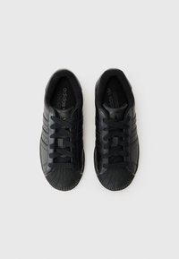 Melnie Adidas sporta apavi izceļas ar teksturētu gumijas purna aizsargu, šņorēšanas dizainu, trim svītrām un gludu ādas virsmu.