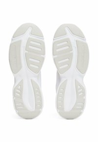 Suole di scarpe sportive bianche con superficie testurizzata, caratterizzate da un motivo in rilievo e fori di ventilazione. Logo presente su una suola.