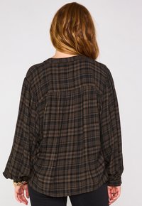 Camicia a quadri nera e marrone con vestibilità ampia, maniche lunghe e orlo arrotondato. Realizzata in tessuto morbido con una finitura testurizzata e una leggera caduta.