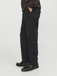 I pantaloni neri su misura presentano un design a gamba dritta con tasche anteriori e una texture del tessuto liscia, indossati con scarpe nere stringate.
