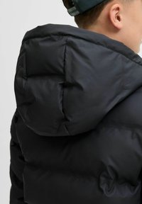 Veste puffer noire avec capuche, présentant une texture lisse et brillante. Conçue en matériau matelassé avec une apparence légère et volumineuse.
