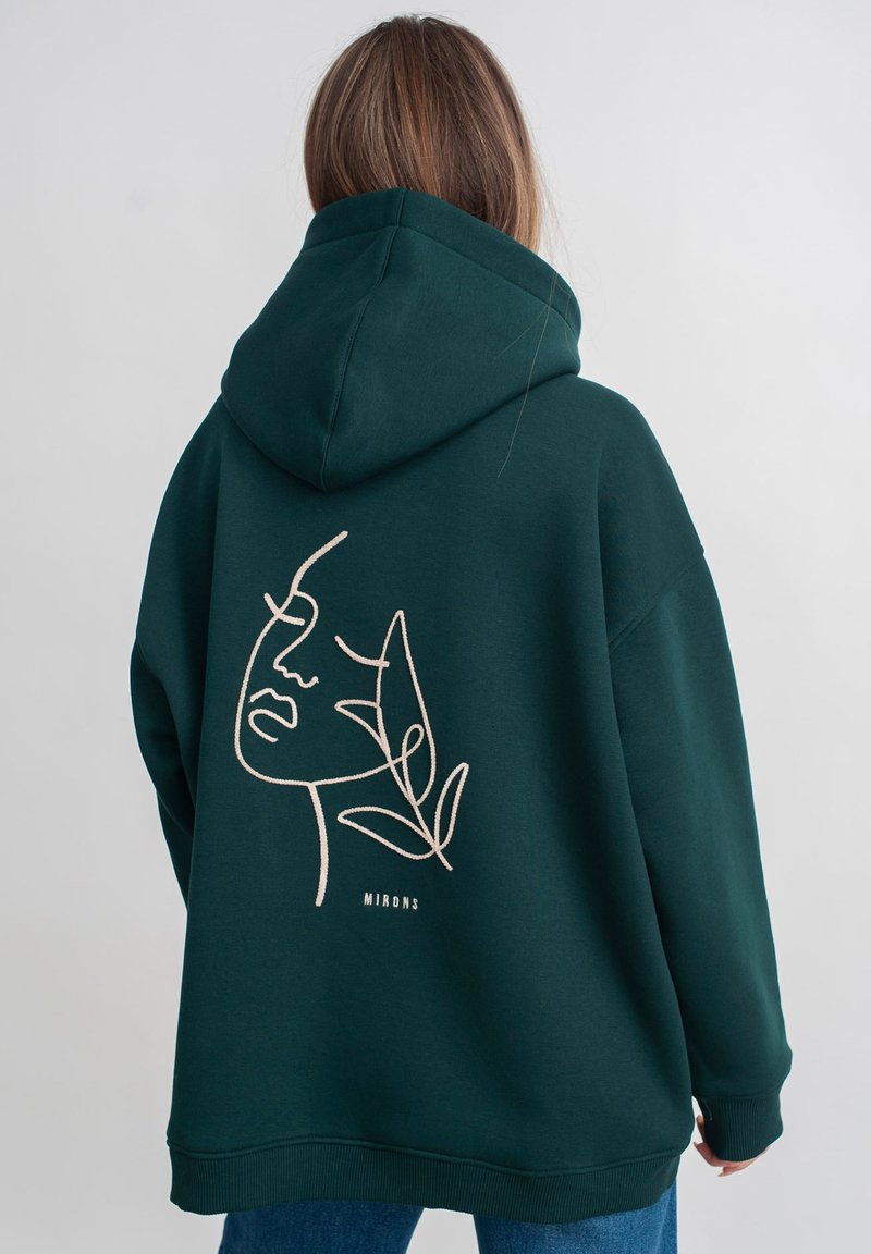Groene hoodie met een minimalistische lijntekening van een gezicht en bladeren op de achterkant, gemaakt van zachte stof met geribbelde manchetten.