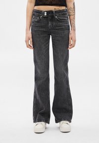 Čierne rozšírené džínsy z denimu s vyblednutým efektom. Majú zapínanie na gombík, pútka na opasok a minimálne prešitie.