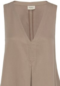 Haut beige sans manches à col en V avec une couture centrale et un tissu subtilement texturé, avec une étiquette de la marque fransa au niveau de l'encolure.