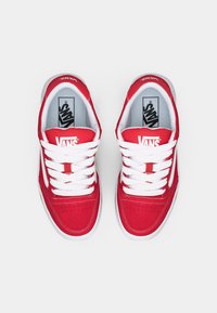Adidași Vans roșii cu șireturi albe, superior din suede, guler căptușit și perforații pe vârf. Tălpică plată din cauciuc alb și logo pe limbă.