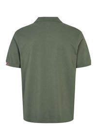 Polo à manches courtes uni de couleur vert foncé, vu de dos avec une petite étiquette rouge et blanche sur la manche gauche.