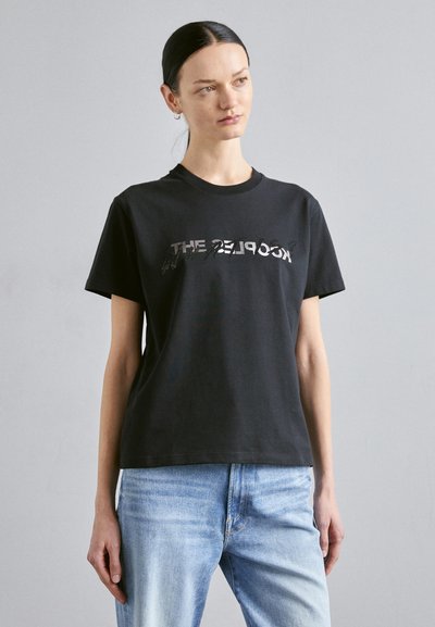 T-shirt in cotone nero caratterizzato da lettere metalliche audaci sulla parte anteriore. Collo tondo classico e maniche corte con una vestibilità rilassata.