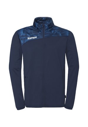 Veste zippée bleu marine avec col montant, empiècement à motif géométrique et logo "Kempa" sur la poitrine gauche.