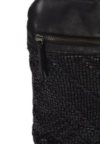 Sac tissé noir avec un motif texturé, présentant des accents en cuir lisse et une fermeture éclair en haut. Design durable et compact.