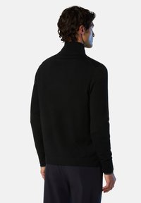 Maglione nero a maniche lunghe con collo a imbuto, in una texture morbida, design aderente con polsini e orlo a coste, visto da dietro.