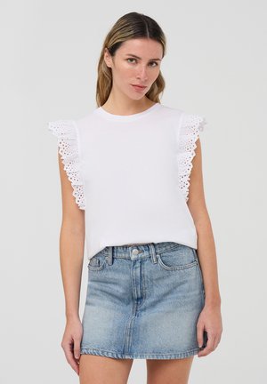 T-shirt bianco con maniche a volant bordate in pizzo, abbinato a una mini gonna in denim chiaro, con vita e una leggera sfumatura.