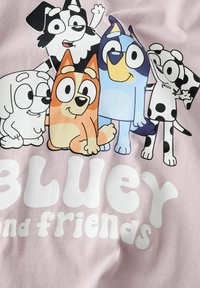 Fem färgglada tecknade hundar står nära varandra med texten "Bluey och vänner" på en rosa bakgrund.
