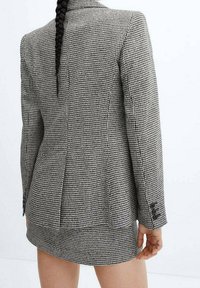 Sada skládající se z blejzru a minisukně v černo-bílém vzoru psí zub, texturovaná látka, střih na tělo s nařasením vzadu a detaily na knoflíky.