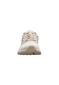 Zapatilla deportiva beige con un upper de malla texturizada, cordones planos y sutiles acentos a rayas. Cuenta con una suela acolchada para un mejor agarre.