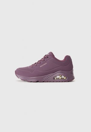 Purple sneaker with a sleek design, textured surface, padded collar, and a visible air unit in the sole. Features round laces and perforations.