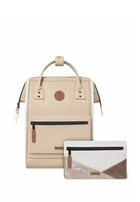 Beiger Textil-Rucksack mit Tragegriff, Vorderfach und Logo. Enthält ein kleineres Täschchen mit einem geometrischen Design in Weiß, Beige und Braun.